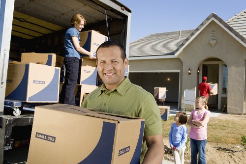 Movers carrying furniture through a typical Acton townhouse entrance